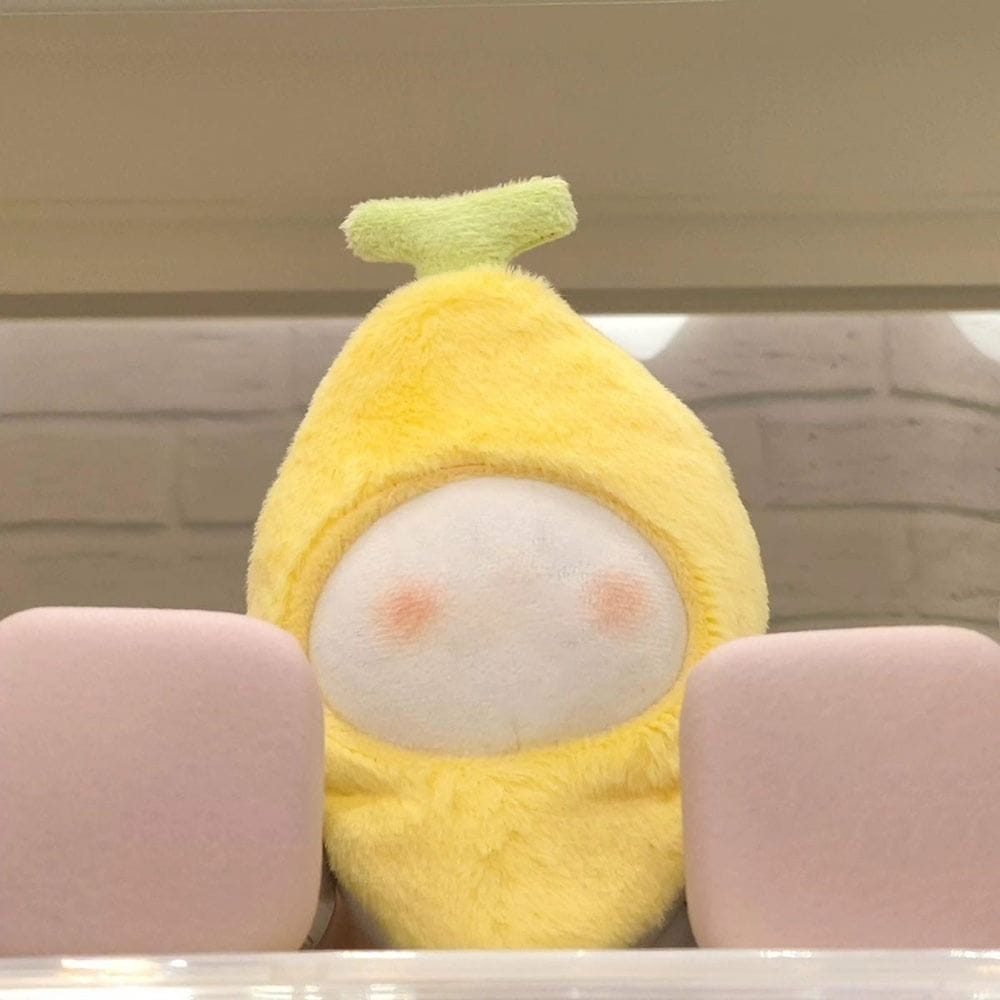 a soft yellow plush doll headgear shaped like a banana with a light green stem and rosy cheeks measuring 10cm