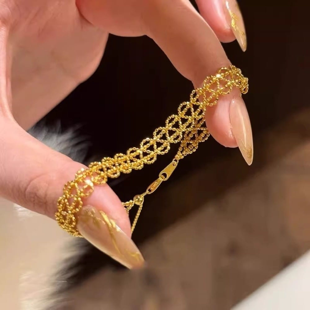 A delicate gold metal lace bracelet with an intricate interlocking mesh design and a small clasp adjustable for fashion jewelry.
