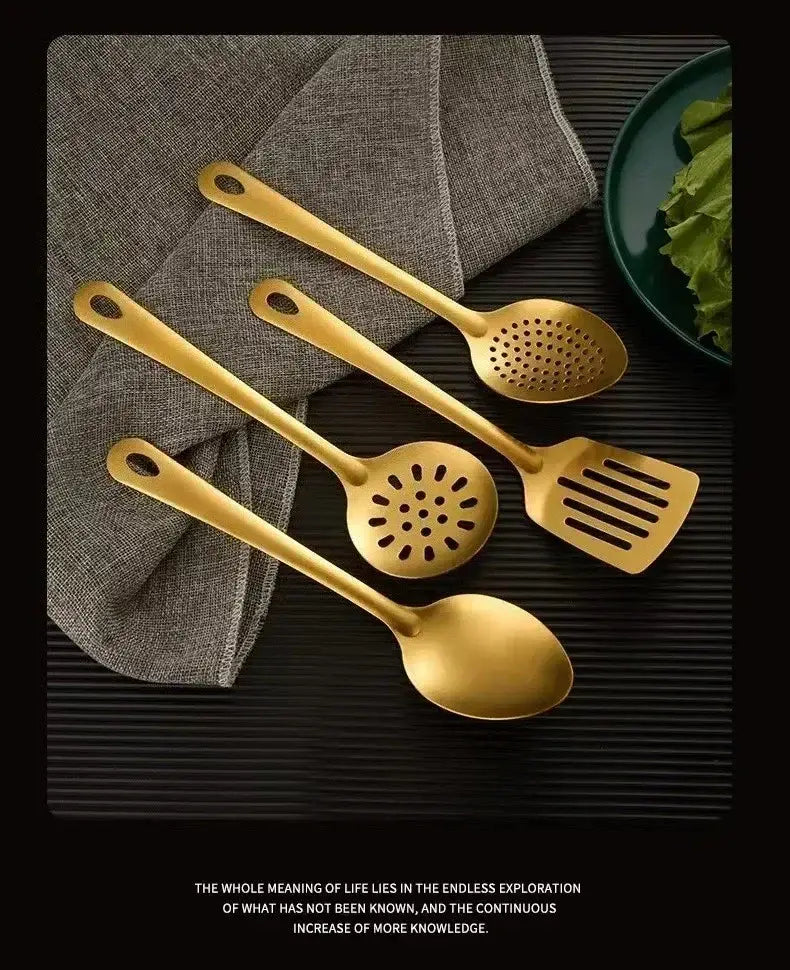 set of four gold kitchen utensils made of stainless steel with sleek modern handles and perforated or slotted heads for cooking tasks