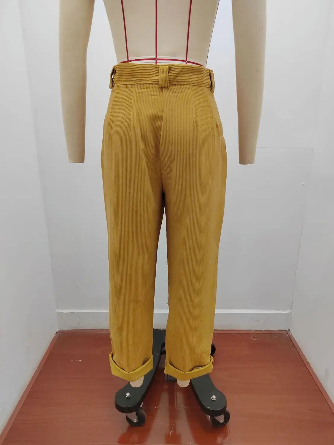 Pantalon en velours côtelé jaune moutarde taille haute ample avec ceinture et bas retroussés, conçu pour un look décontracté mais élégant.