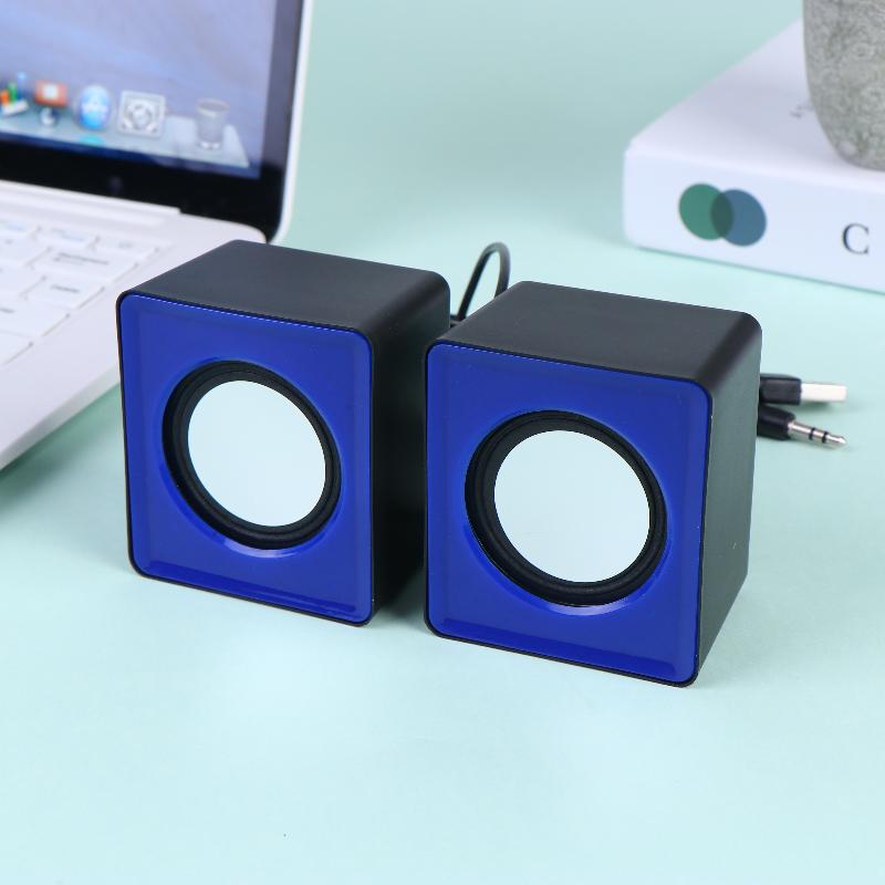 Une paire de mini haut-parleurs de bureau USB compacts en forme de cube, bleus et noirs, avec des haut-parleurs circulaires blancs pour l’audio stéréo sur ordinateur.