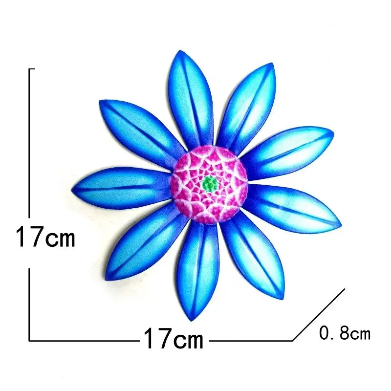 A vibrant blue metal flower wall art sculpture with a pink and green detailed center measuring 17cm by 17cm.