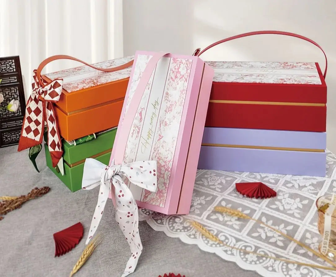 Coffret-cadeau de mariage de luxe pour la demoiselle d’honneur et le meilleur ami, présentant un coffret rectangulaire rose avec un motif floral et un ruban blanc à pois noué en forme de nœud.