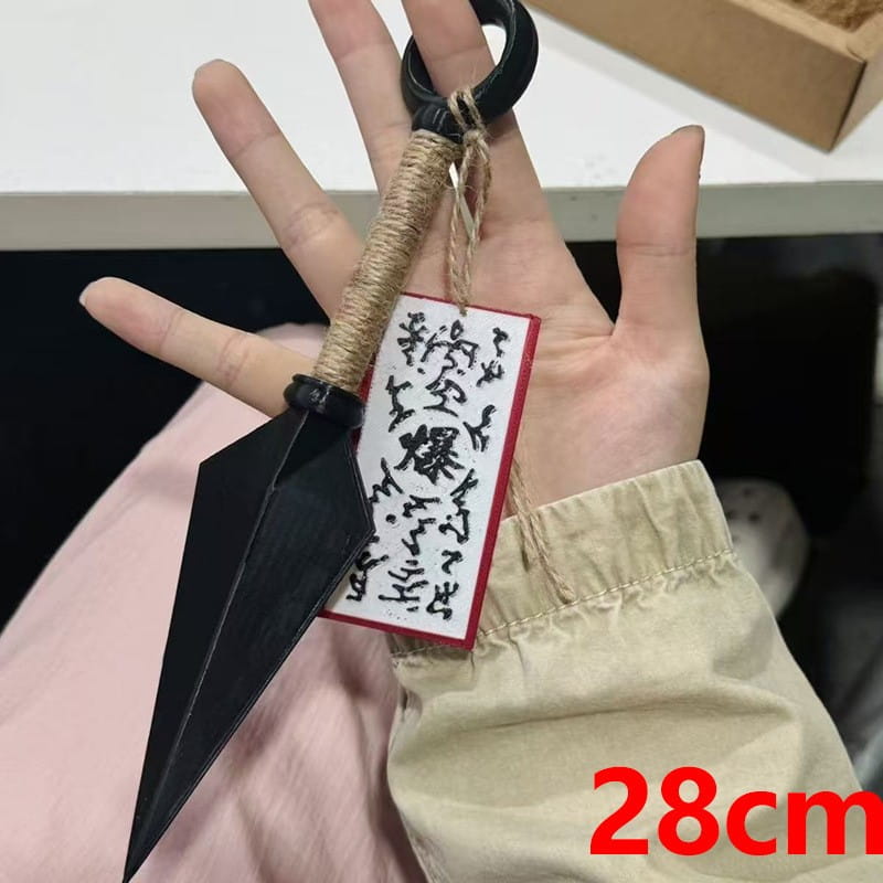 Kühlschrankmagnet aus schwarzem Kunststoff in Form eines Ninja-Kunai mit seilumwickeltem Griff und einem schwarzen, kreisförmigen Ring aus PVC, als Shuriken-Spielzeug.