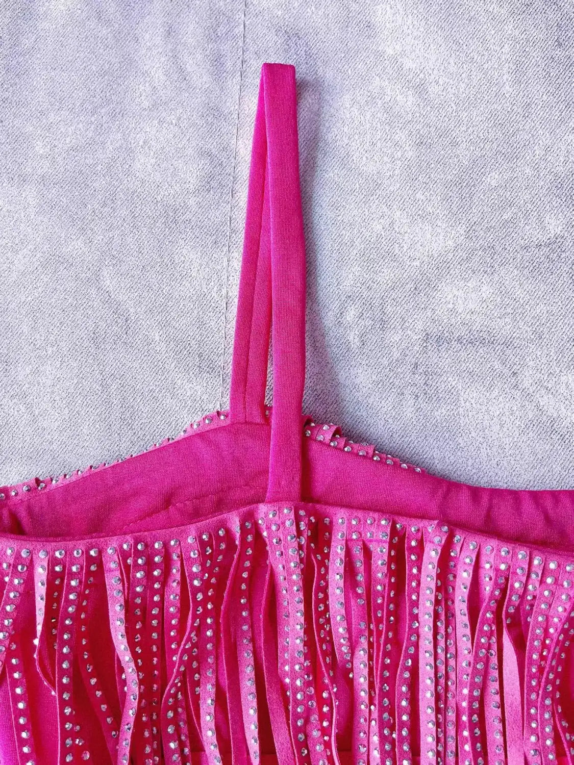 Mini-jupe taille haute fuchsia rose vif à franges en strass, avec des détails délicatement frangés et des ornements en strass scintillants le long des lanières.