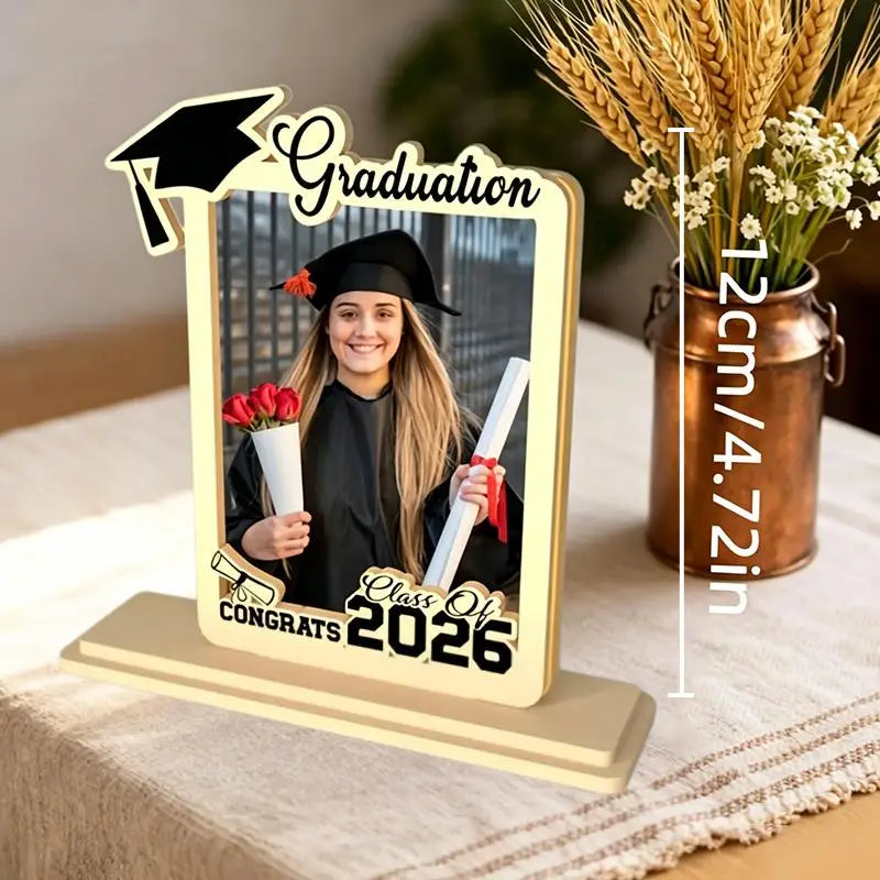 Beige wooden graduation photo frame with black and white decorative elements featuring a mortarboard and class of 2026 text for displaying commemorative photos.