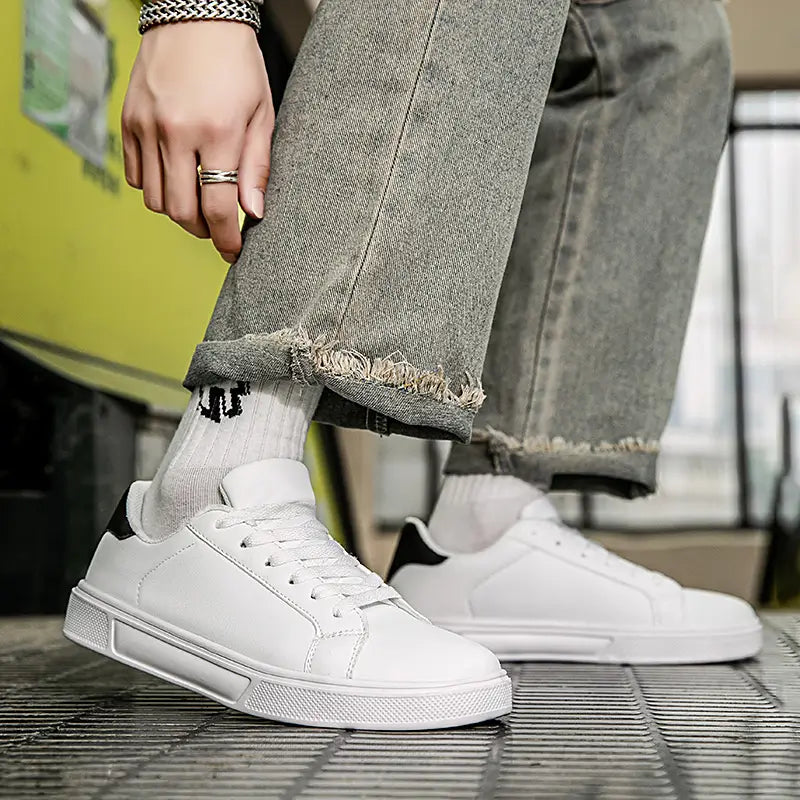 Weiße Ledersneaker im Freizeitstil, leichte Sportschuhe, mit einer klaren lederähnlichen Oberseite, schwarzen Akzenten an der Ferse und der Zunge sowie einer strukturierten Gummisohle.
