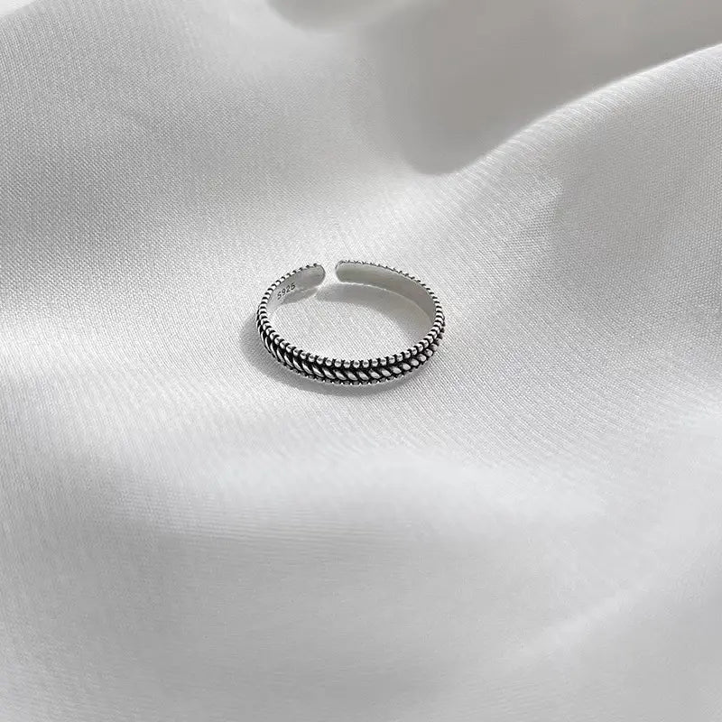 Un anillo para el dedo del pie trenzado de plata 925 de plata de ley, con un diseño trenzado y texturizado.
