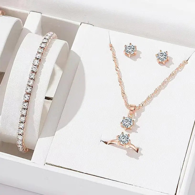 Juego de joyería de 5 piezas con circonitas cúbicas de color dorado rosado engastadas con circonitas tipo diamante, que incluye un collar, aretes, una pulsera y un anillo con piedras de circonita cúbica transparente.