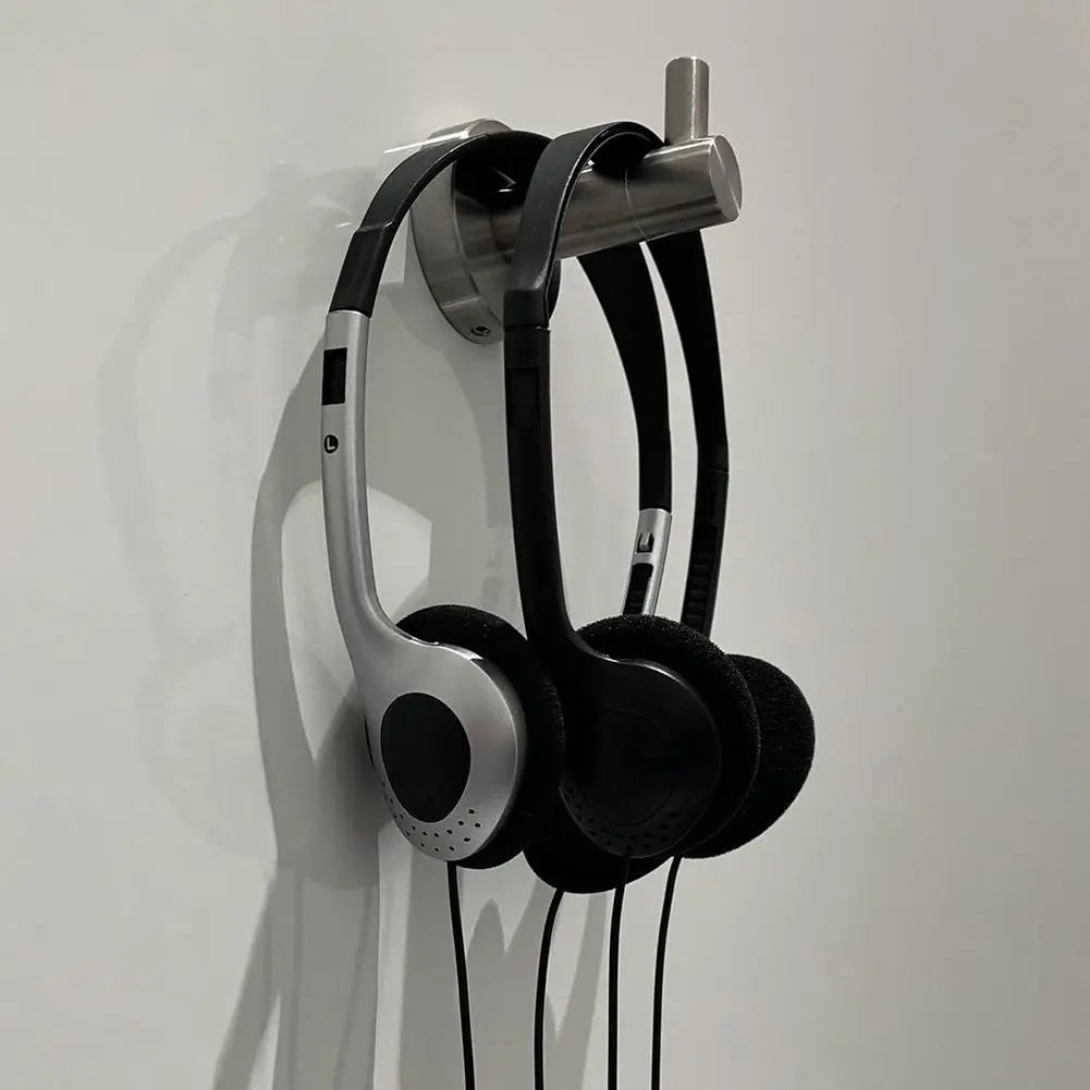 Casque d’écoute supra-auriculaire rétro filaire noir et argent avec coussinets d’oreille rembourrés, suspendus à un support mural métallique.