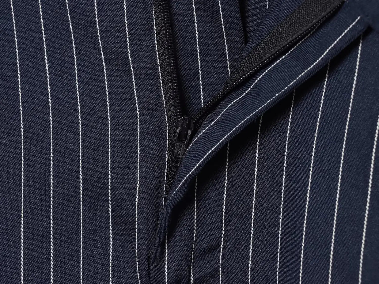 Chaqueta sastre azul marino de pinstripe con rayas verticales blancas y cremallera negra, combinada con una falda maxi azul marino a rayas de tiro alto.