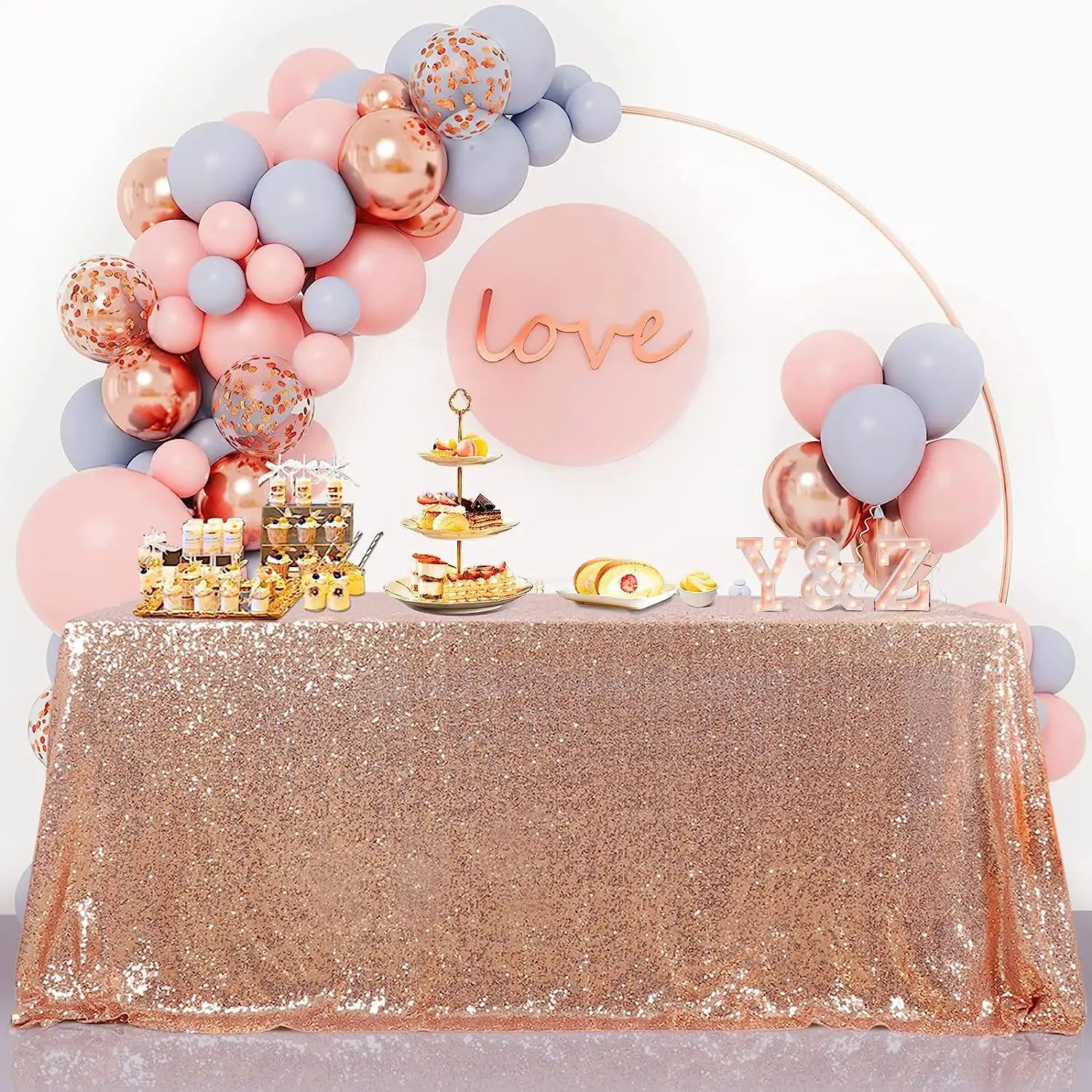 Nappe à paillettes dorées rosées présentée à côté de sacs de stockage sous vide avec pompe manuelle, conçue pour la compression et le rangement de la literie et des vêtements.