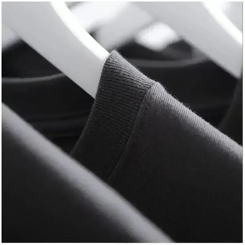 Schwarzer gerippter Rundausschnitt des Tactical-Angel-Graphic-Cotton-T-Shirts, der an einem weißen Bügel hängt.