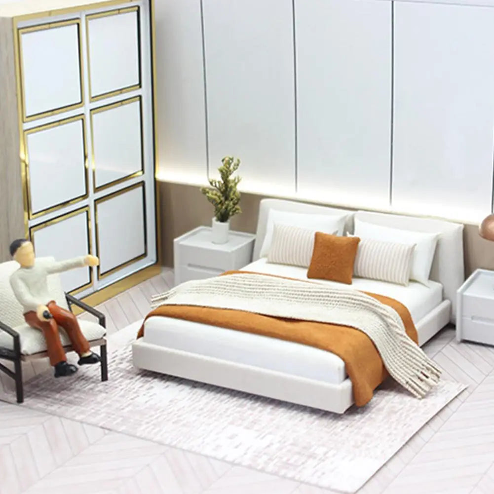 White miniature dollhouse double platform bed with cream bedding featuring a textured orange throw blanket and matching accent pillow.