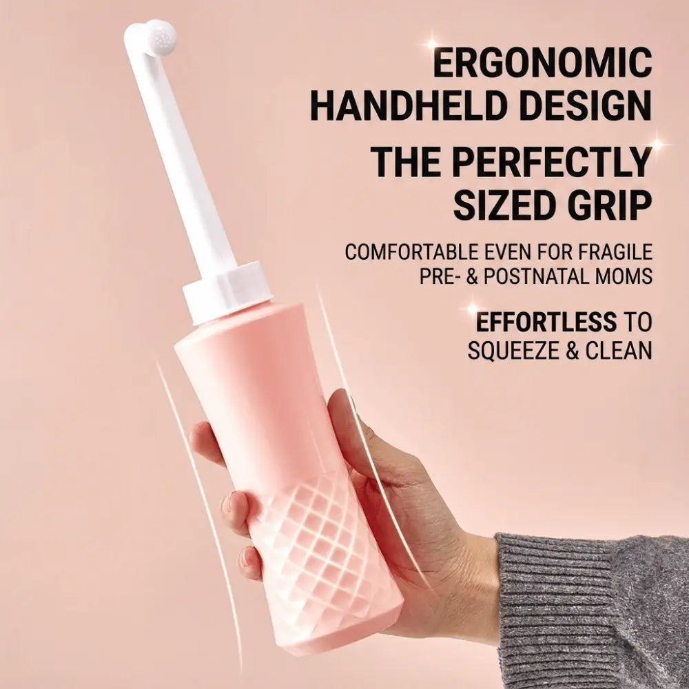 Eine rosafarbene ergonomische Hand-Peri-Flasche mit weißem Auslauf und strukturiertem Griff, ausgelegt für die perineale Reinigung im Wochenbett.