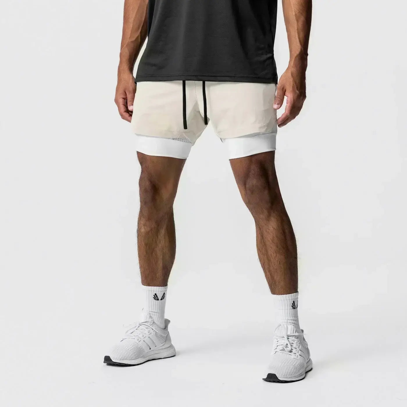 Hombres, pantalones cortos atléticos 2 en 1 de color crema para gimnasio con un diseño moderno y elegante, que incorporan cordones negros, cintura elástica y trabilla para la toalla para entrenamientos convenientes.