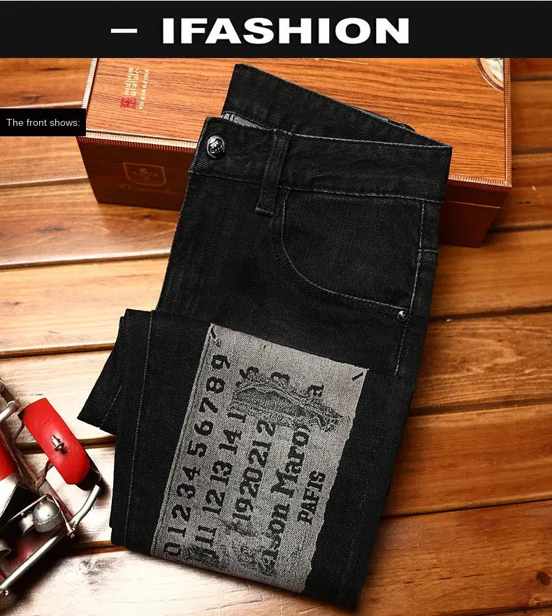 Mens slim fit printed black denim jeans featuring a gray patch with vintage-style text and an illustration on the back side.