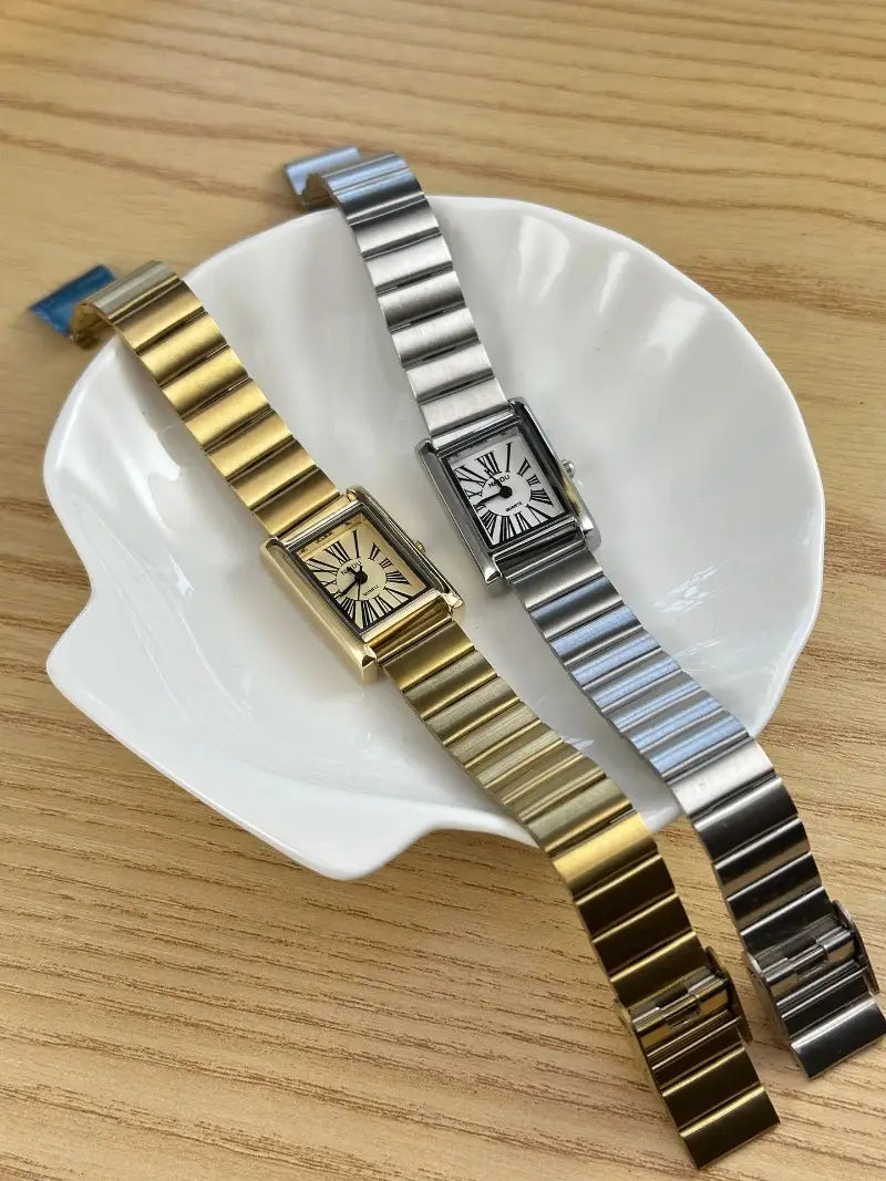 Two rectangular-faced wristwatches featuring classic roman numeral dials in gold-tone and silver-tone, showcasing vintage gold rectangular quartz watch for women.