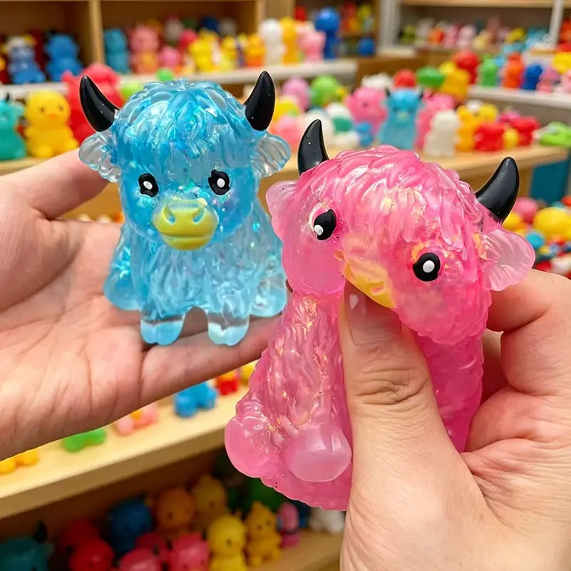a translucent blue and pink highland cow sensory fidget toy with black horns, yellow nose, and glossy eyes designed for stress relief