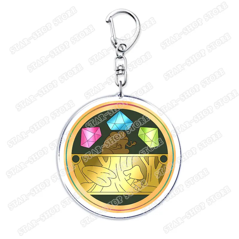 Circular acrylic Amphibia anime keychain featuring a cartoon frog with pink, blue, and green gemstones and golden leafy designs on a dark background.