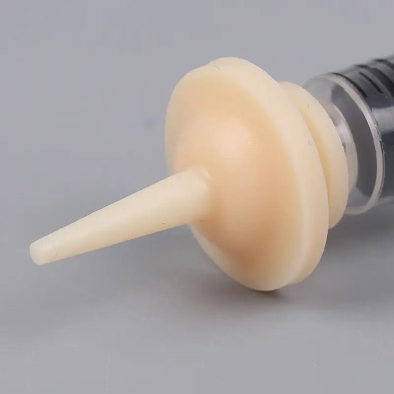 cream-colored silicone nipple shield attached to a syringe in a pet oral syringe feeding set with silicone nipples for safe and effective feeding.