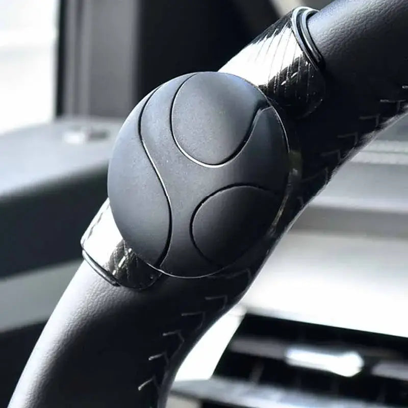Black spherical steering wheel spinner knob with matte finish and subtle curved grooves designed for 360 degree turn assist.