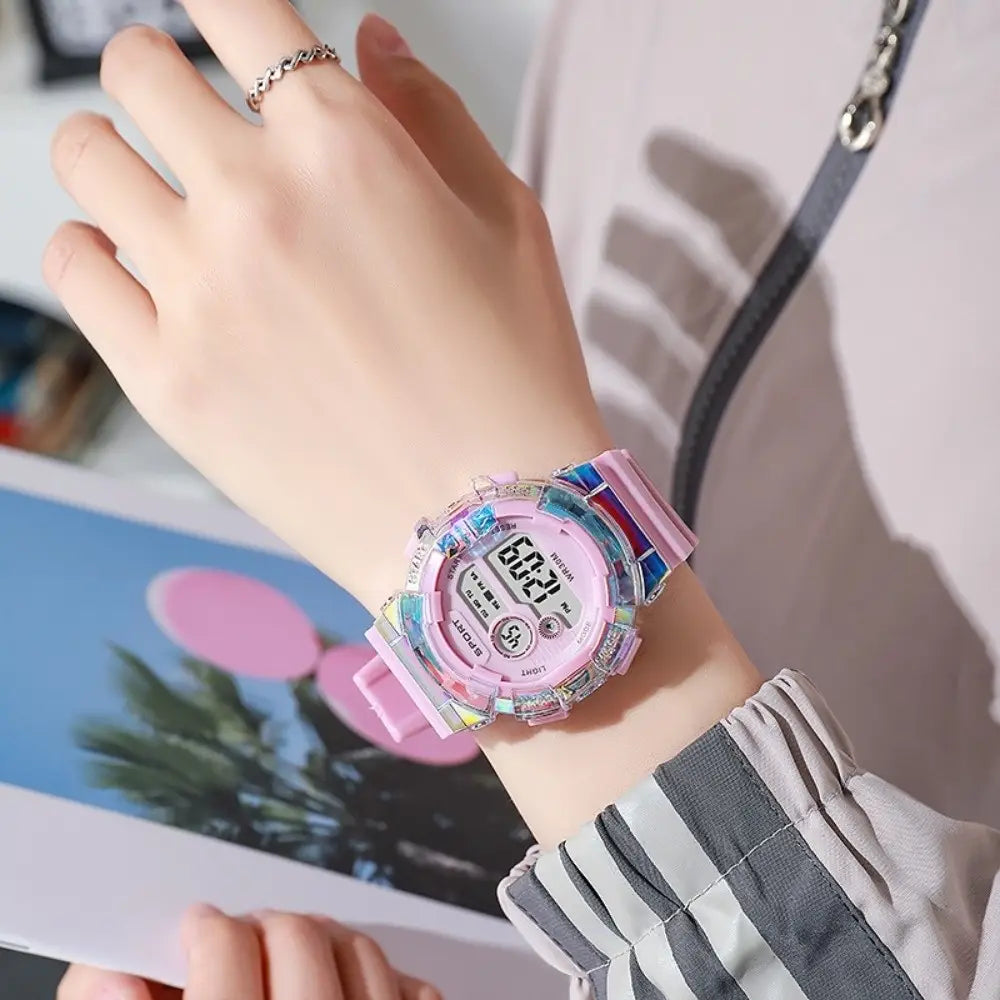 reloj digital deportivo para niños rosa pastel que presenta una caja de resina translúcida de color arcoíris y material de correa de silicona, con batería incluida