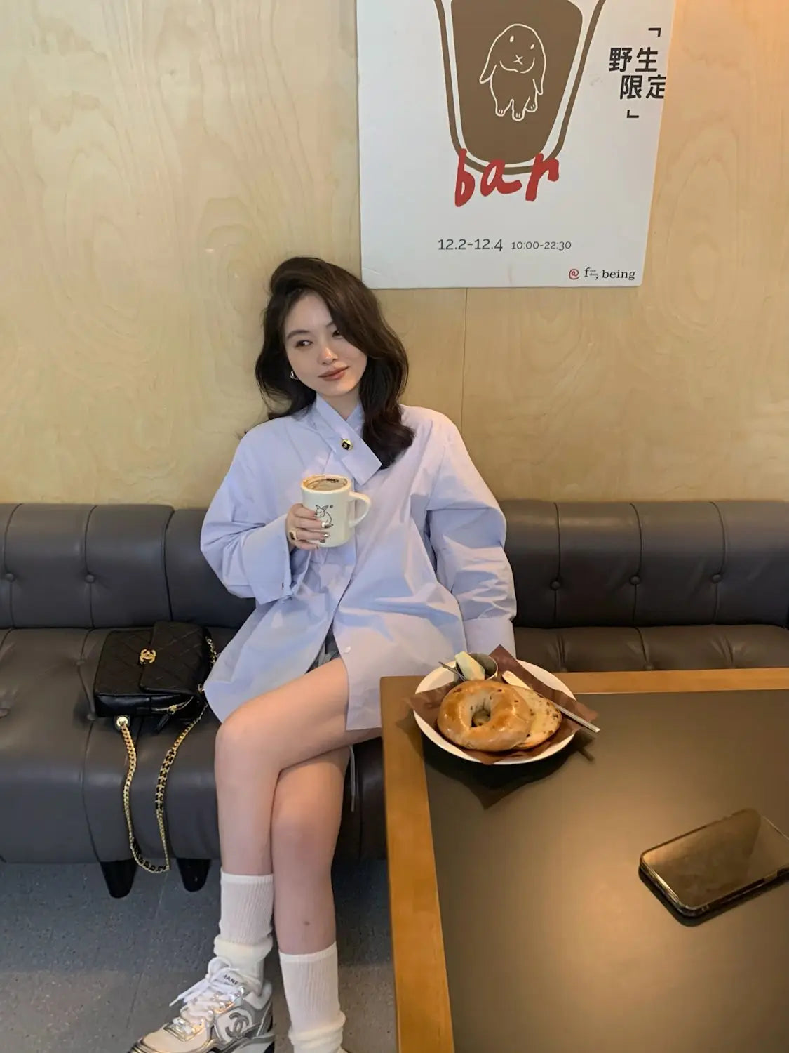 black leather Chanel handbag with gold chain strap paired with light blue oversized button up shirt displayed as a fashion ensemble