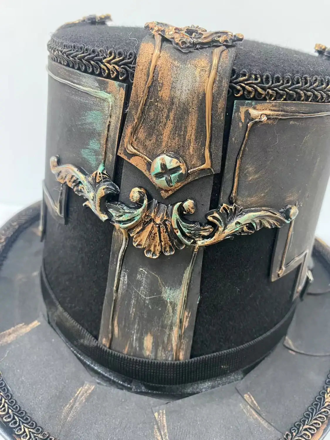 Black steampunk top hat with ornate gold and bronze detailing, featuring a decorative buckle and intricate filigree accents.