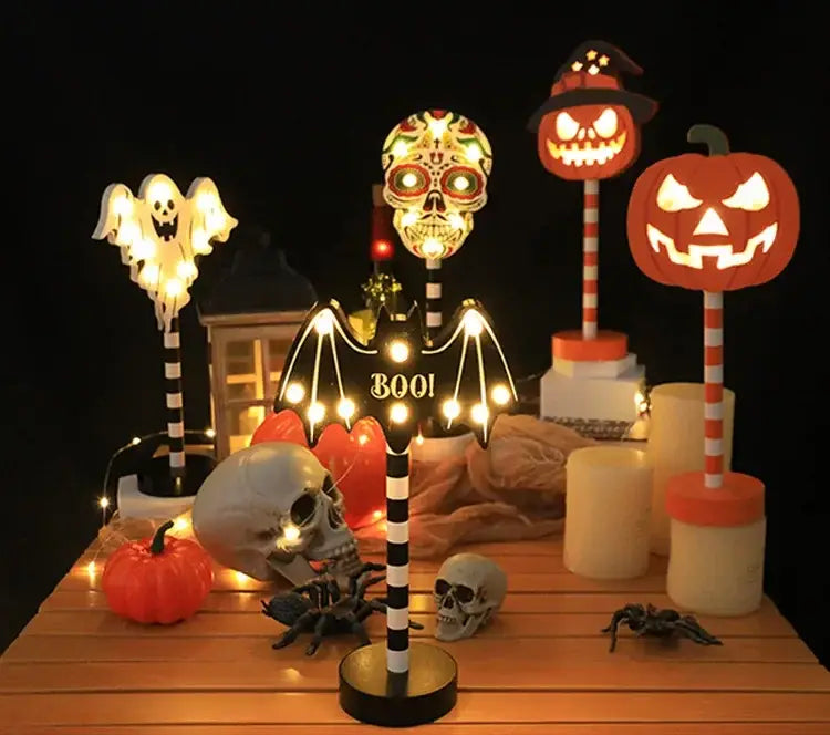 Eine leuchtende Halloween-Dekoration für eine Nachtlampe in Schwarz-Weiß, im Fledermaus-Design mit Streifen, mit Zuckerschädel-Kopf und beleuchteten Lichtern entlang der Flügel, die „Boo“ formen.