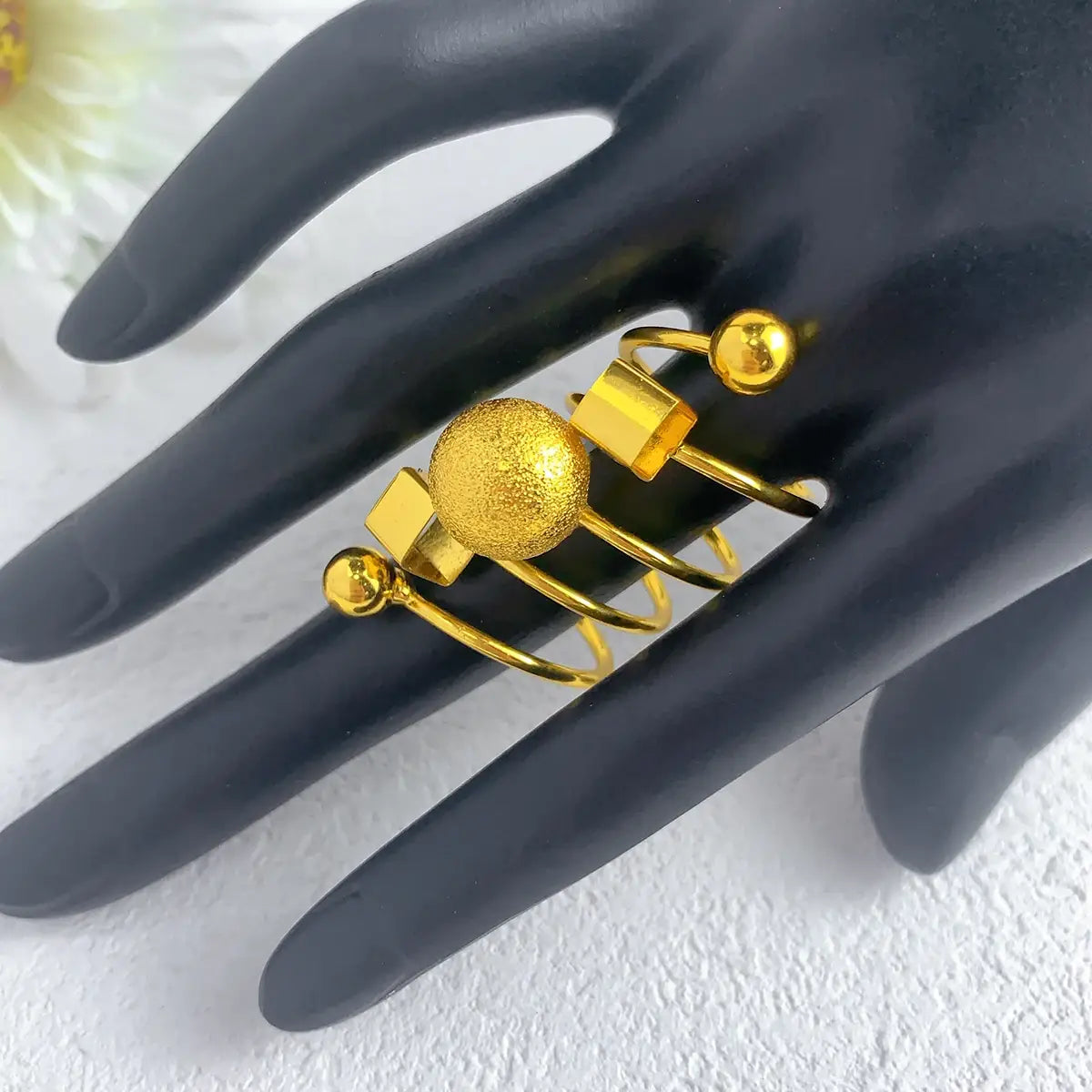 24k gold plated dubai jewelry spiral ring for women featuring a gold-toned multi-ring set with a textured spherical centerpiece, square accents, and small polished spheres on slender bands.