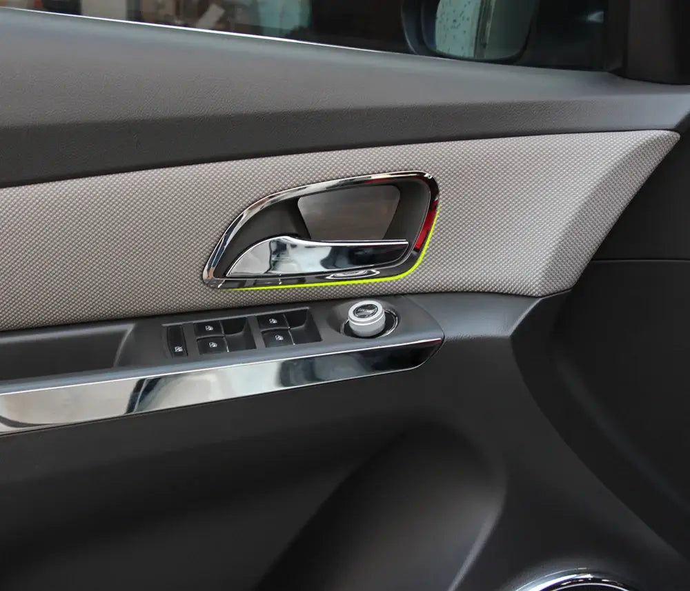 Moldura de manija interior de la puerta con acabado en cromo y diseño moderno y elegante, colocada sobre una moldura de tela gris texturizada para Chevrolet Cruze 2009-2014.