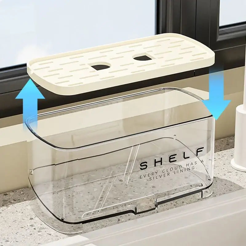 Organizador transparente de fregadero de cocina de plástico con sistema de drenaje, con tapa perforada de color crema que presenta dos recortes y texto de ribete plateado impreso en el lateral.