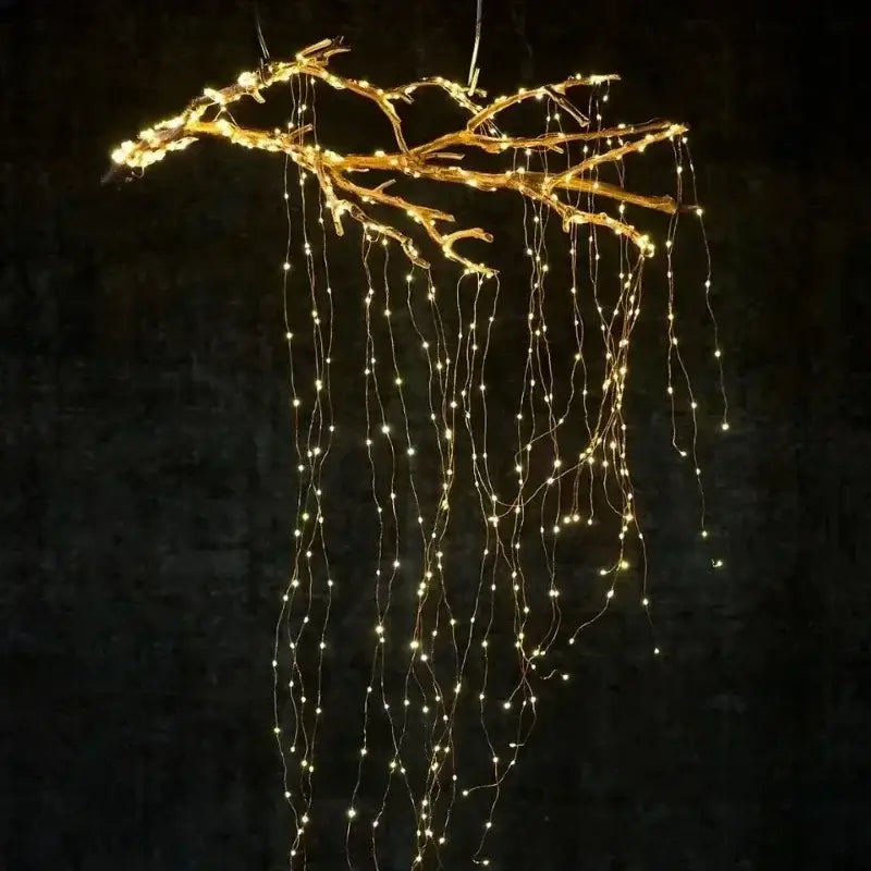 un luminaire suspendu en forme de branche dorée, orné de guirlandes lumineuses à DEL à fil de cuivre blanc chaud, vu de face