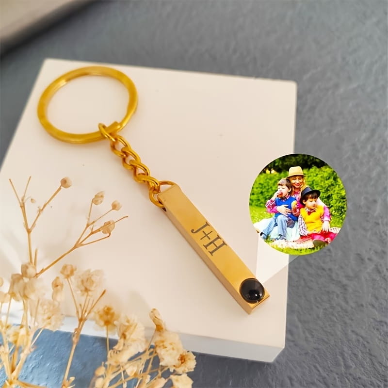 gold-colored rectangular metal custom photo projection keychain with engraved initials j+h and a black gemstone at one end personalized as a metal gift