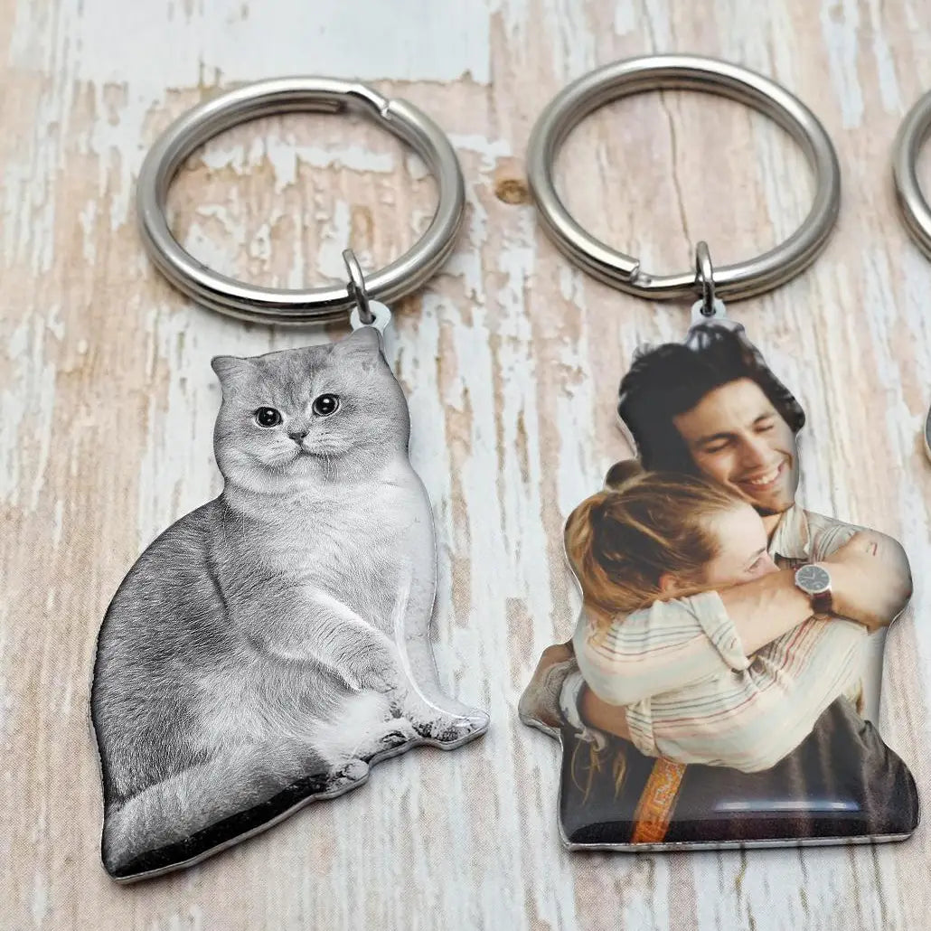 Silver-colored custom photo keychains made of metal featuring a detailed cat silhouette and a couple embracing in a personalized picture keyring design.