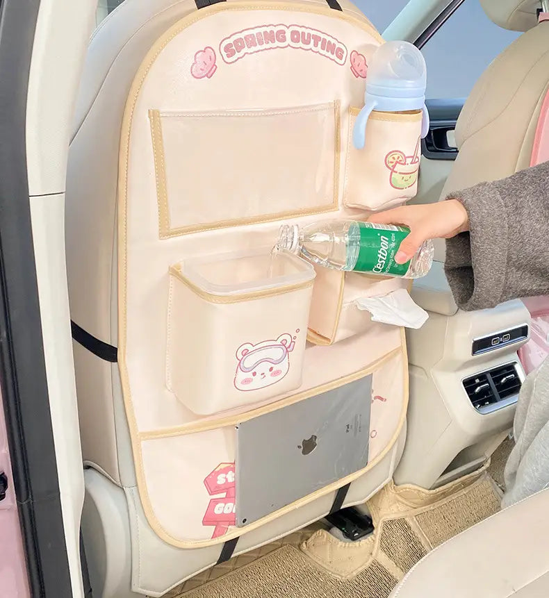 Organizador para el asiento trasero del coche en beige, fabricado con material resistente, con texto de salida primaveral rosa y diseños de osito de dibujos animados, con múltiples bolsillos, incluido un pequeño cubo de basura para un almacenamiento conveniente.