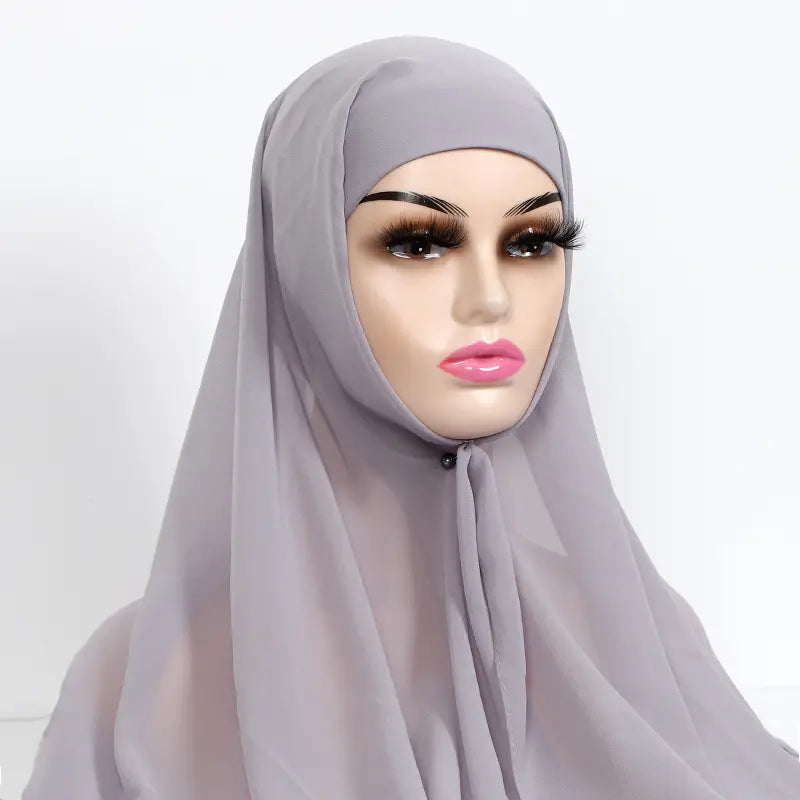 A soft light gray instant chiffon hijab with cap bonnet made of sheer fabric drapes elegantly over a mannequin head.