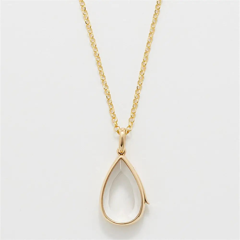 Collier pendentif ouvert délicat en or pour femmes et jeunes filles, style simple, présentant une pierre précieuse facettée transparente montée dans un cadre en forme de goutte en or poli.