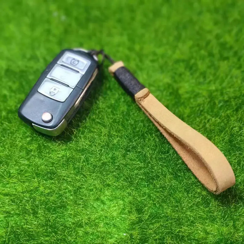 Black car key fob with tan leather wrist strap attached to leather weave lanyard keychain car key holder.