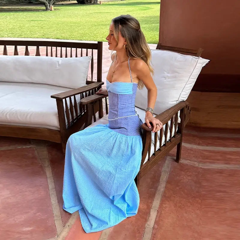 Eine Frau trägt ein zweiteiliges Set aus trägerlosem Korsagenkleid, mit einem strukturiertem, tailliertem blauen Oberteil mit elastischer Taille und einem fließenden Rock.