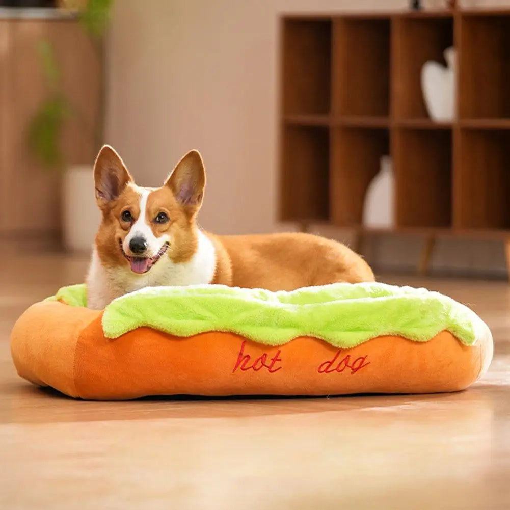 Orange plush hot dog-shaped pet bed with green lettuce trim and red embroidered text designed as a cozy resting place for cats and dogs.