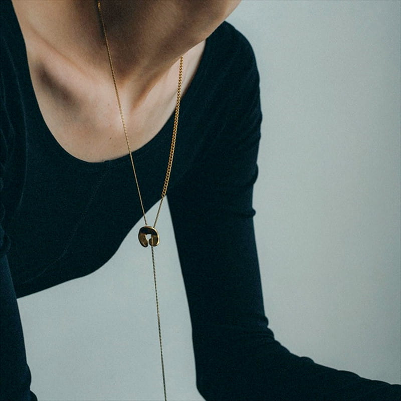 Collier en chaîne aux tons dorés pour femmes, présentant un pendentif circulaire minimaliste à superposition géométrique, avec un design de centre ajouré.