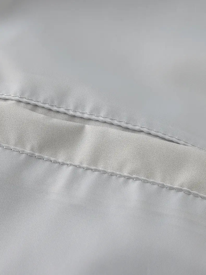 A smooth light gray satin fabric with fine stitching on a waterproof hiking jacket men windbreaker designed for autumn use.