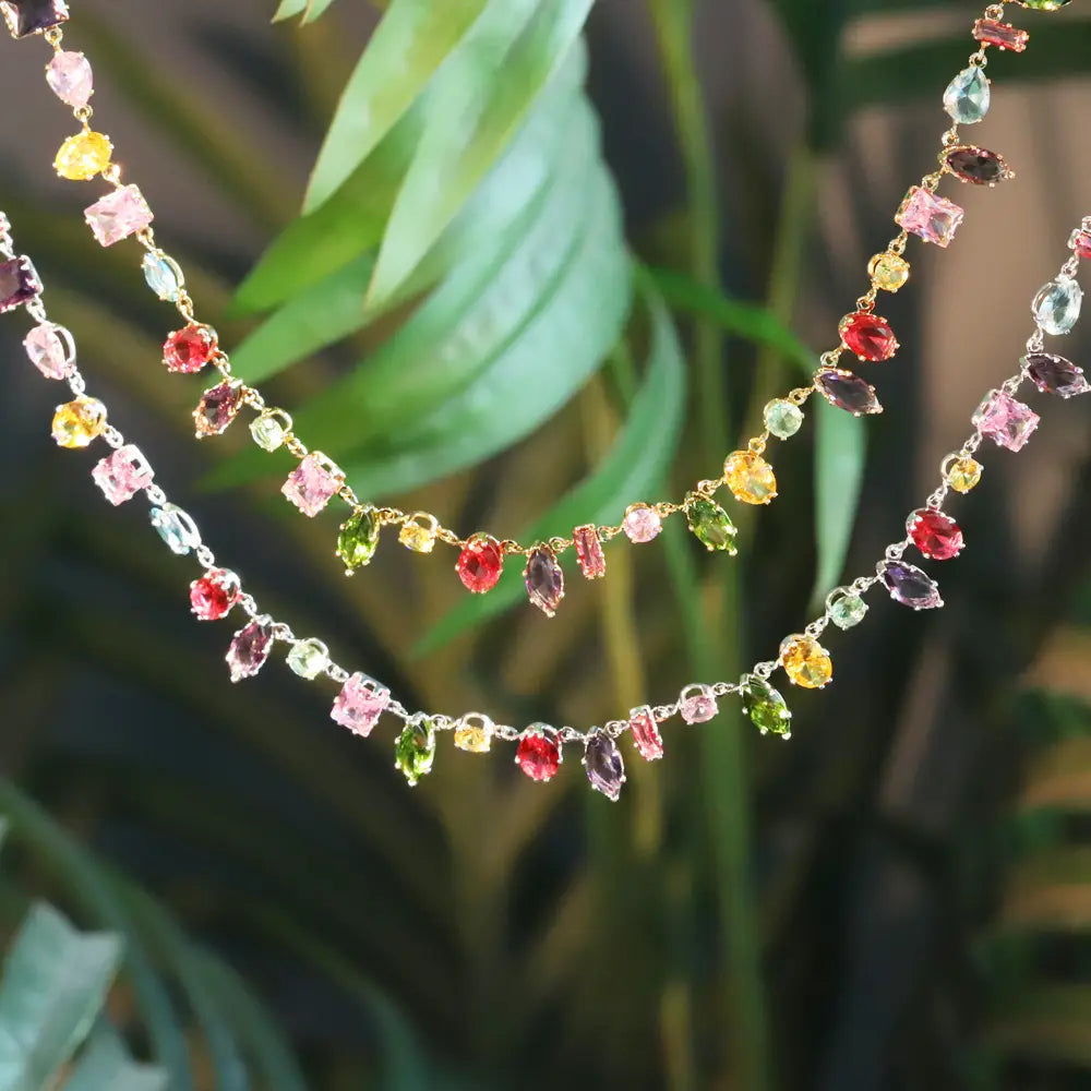 A delicate colorful zircon crystal gold plated necklace featuring vibrant faceted gemstones in pink yellow green red and purple on fine gold toned multi strand chains.