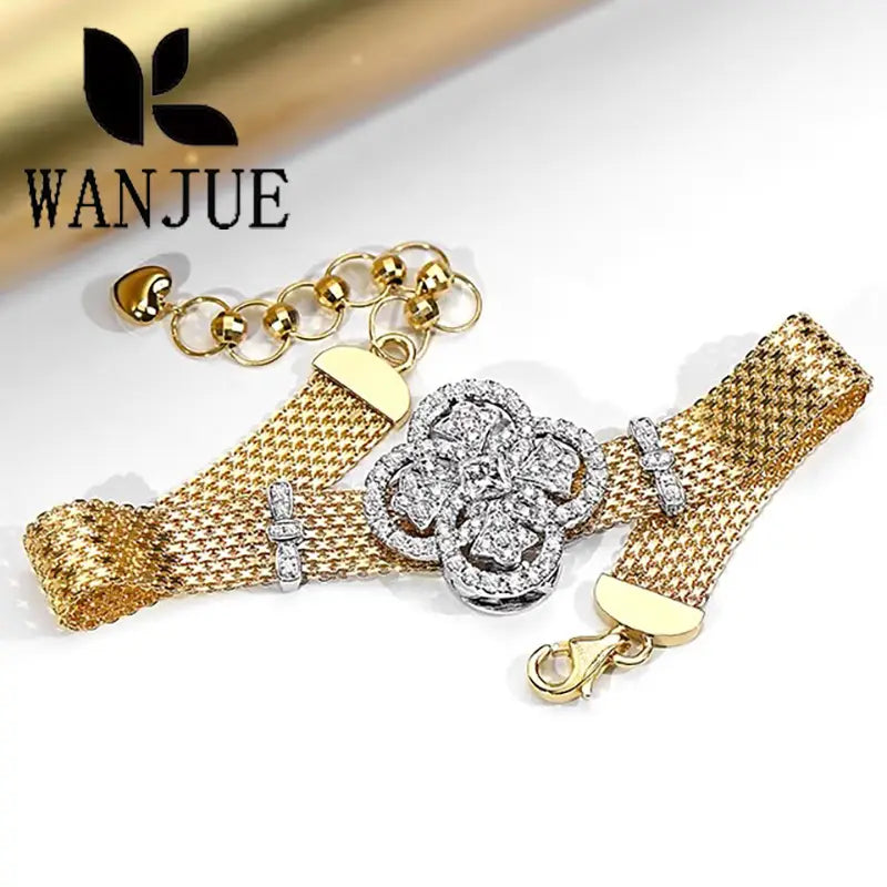 Crystal flower gold mesh cuff bracelet featuring a central silver-toned floral clasp adorned with sparkling diamonds and accented by small diamond-studded clasps.