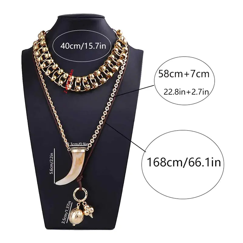 Vintage ethnic layered pendant necklace for women displayed on a black mannequin bust featuring gold-toned chains with a prominent ivory-colored tusk pendant and smaller gold charms.