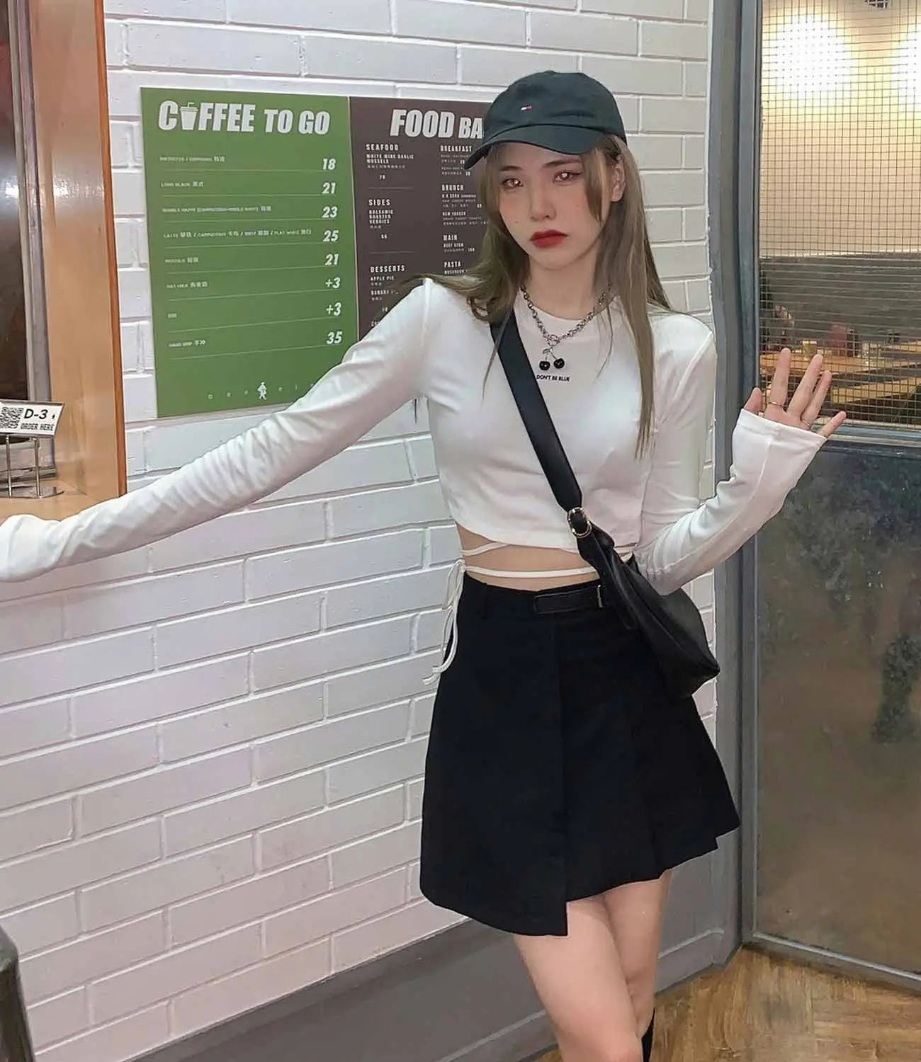Schwarze Umhängetasche mit elegantem, minimalistischem Design und verstellbarem Riemen, kombiniert mit Damen-Langarm-Crisscross-Crop-Top.