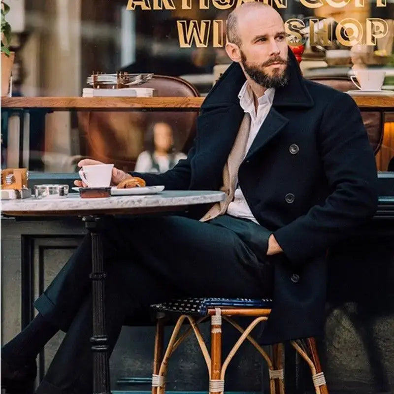 Un hombre que viste un abrigo largo tipo peacoat de lana azul marino oscuro con doble botonadura, chaqueta de invierno, sobre una camisa de vestir de color claro con cuello.