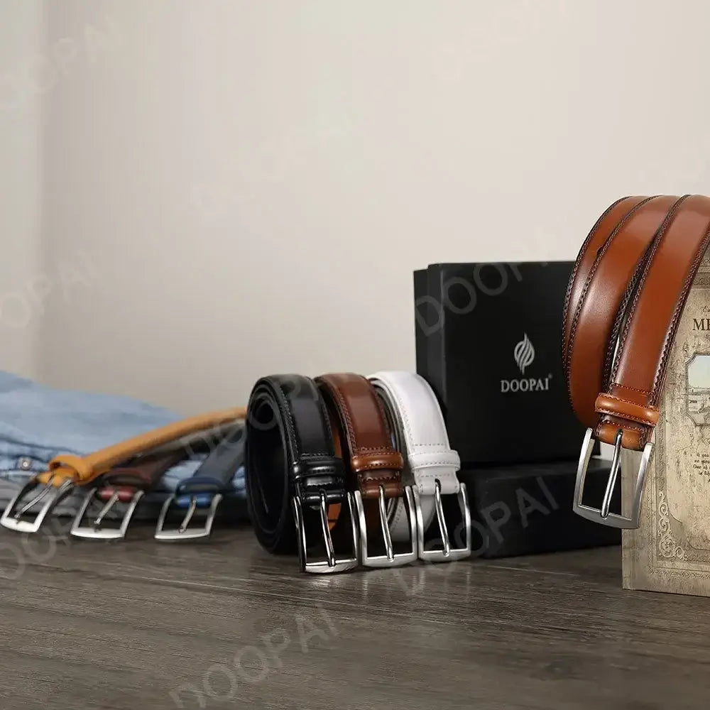 Ceinture à cliquet en cuir pour homme marron, avec boucle automatique à l’aspect argenté, présentée à côté d’autres ceintures de couleurs différentes et d’un emballage de marque.